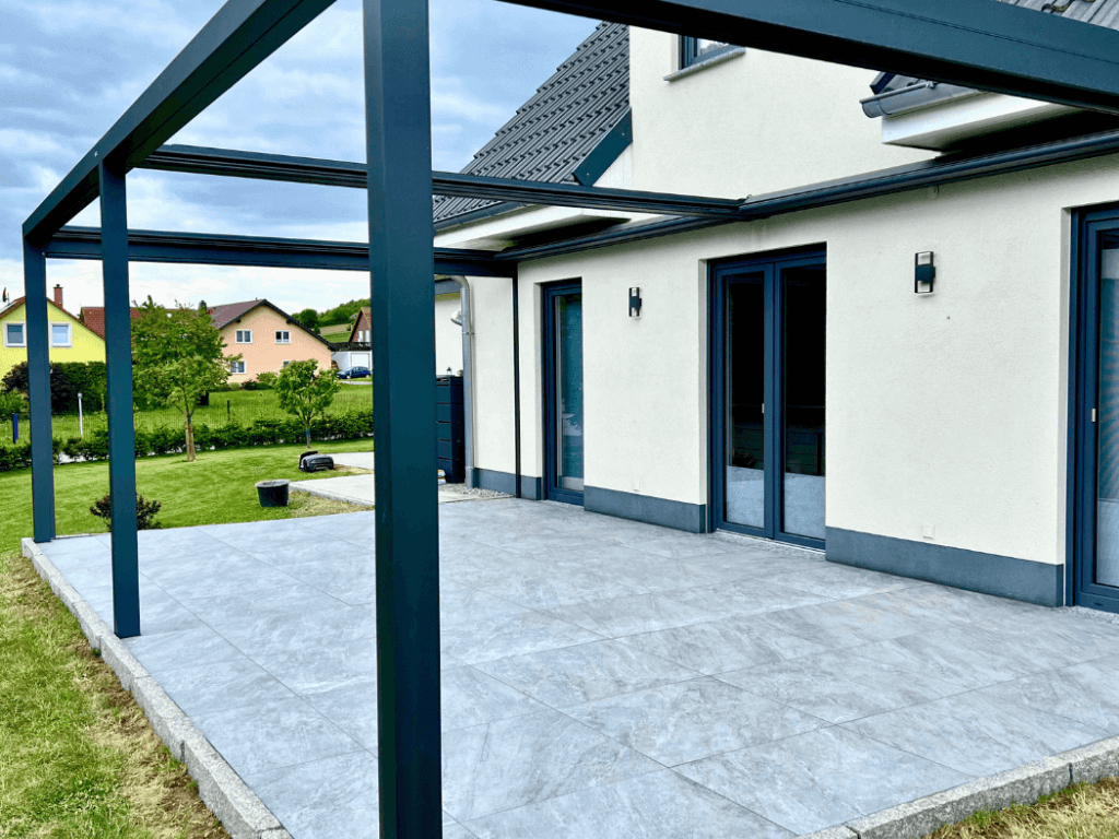 Mitarbeiter verlegt Feinsteinzeugplatten auf einer Terrasse.