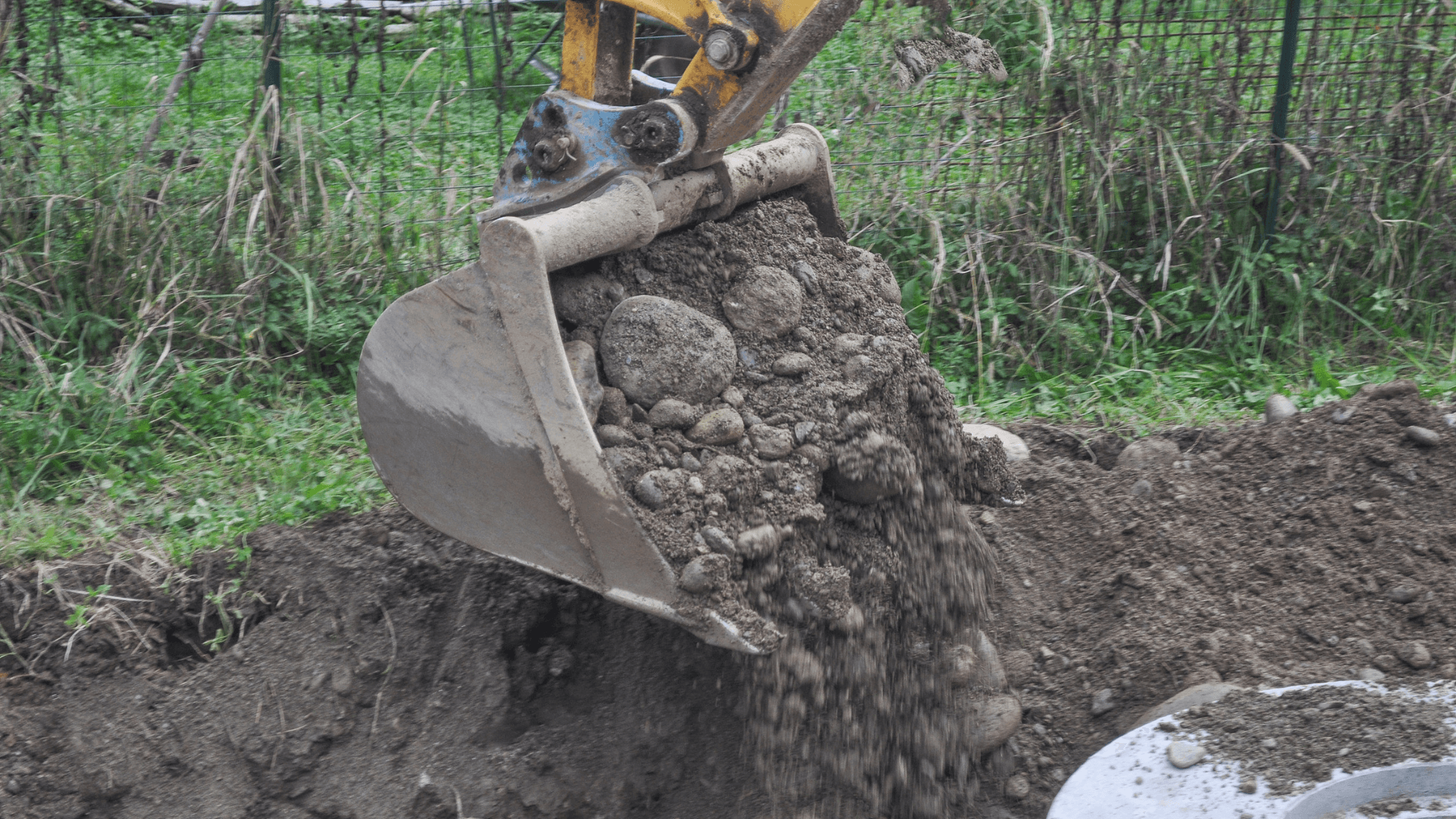 Nahaufnahme eines Baggers, der Erde und Steine aushebt. Baggerarbeiten für Aushub- und Erdbewegungen auf einer Baustelle.