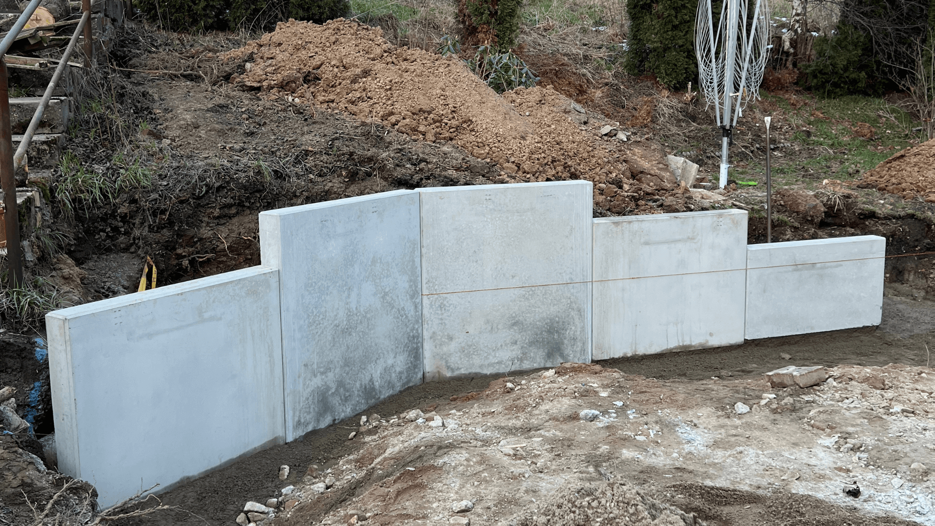 Neu gepflasterter Hofbereich mit grauen Steinen, angrenzend an ein gelbes Haus und eine vorbereitete Gartenfläche.