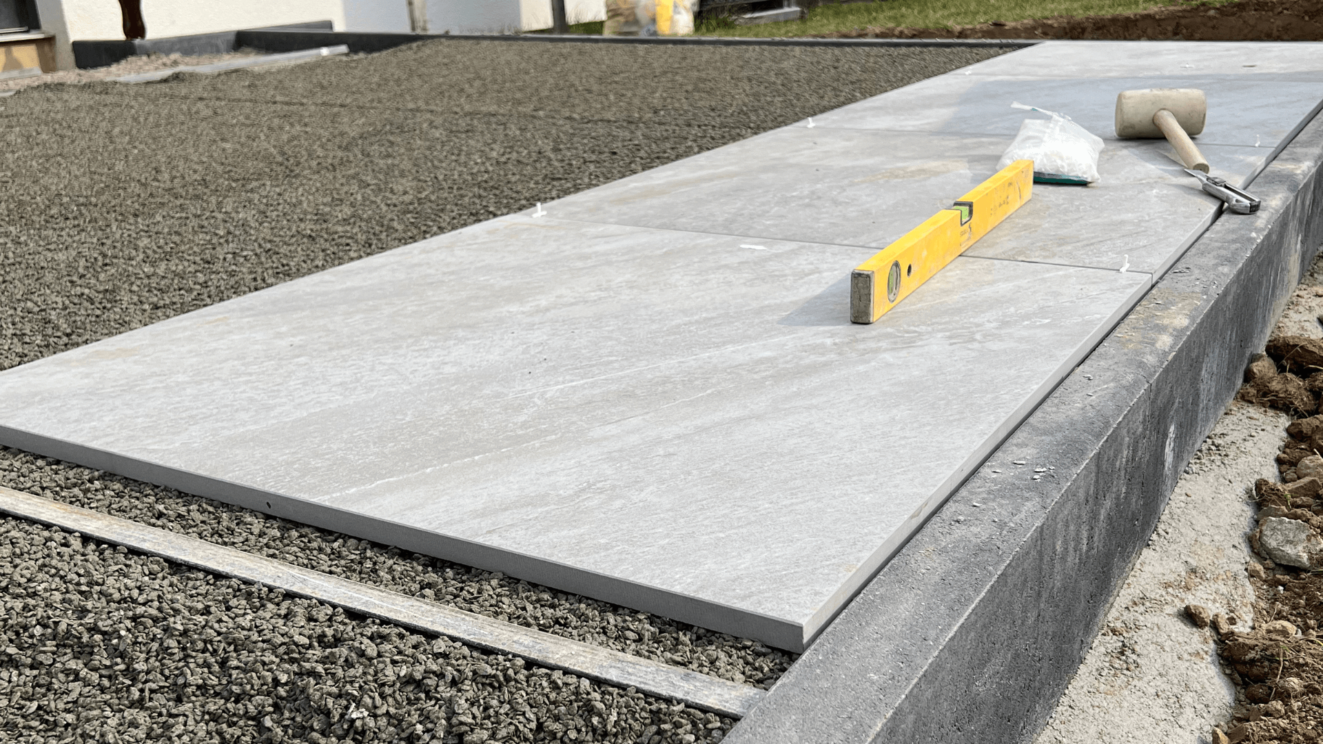 Verlegen von Terrassenplatten auf Splittbett mit Werkzeugen für exakte Ausrichtung