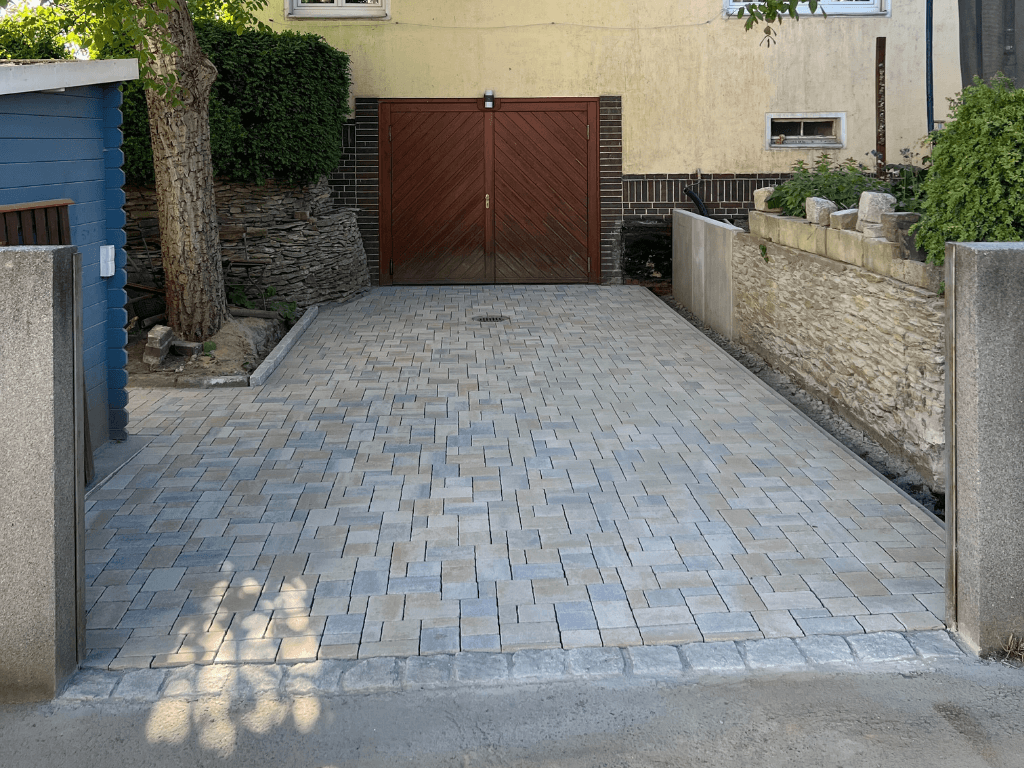 Gepflasterte Einfahrt mit modernen Betonsteinen vor einer Garage in Dresden.